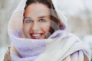 Young woman face covered with light colored knitted scarf