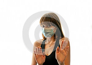 Young woman with face mask backing off from camera while having both hands up in protective manner