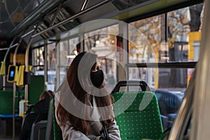 Young woman is face mask is travelling by bus. Precautions in public transport