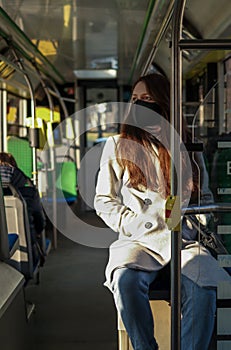 Young woman in face mask is travelling on public transport. Precautions in buse