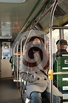 Young woman in face mask is travelling on public transport. Precautions in buse