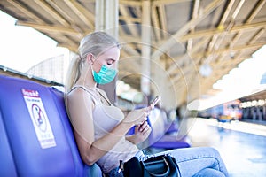 Young woman with face mask waiting in vintage train, relaxed and carefree at the station platform in Bangkok, Thailand