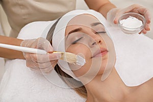 Young woman during face peeling procedure in salon