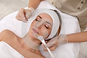 Young woman during face peeling procedure in salon