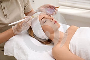 Young woman during face peeling procedure in salon