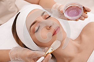 Young woman during face peeling procedure in salon