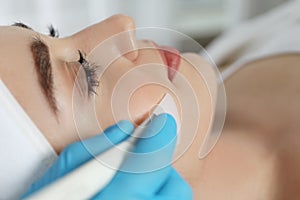 Young woman during face peeling procedure in salon, closeup