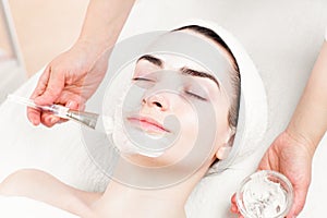 Young woman facial mask applying in beauty parlour photo
