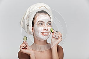 young woman with facial skincare mask and cucumber slices