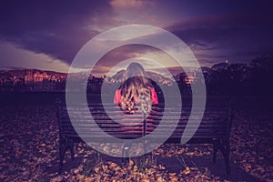 Young woman facing away seated on a bench