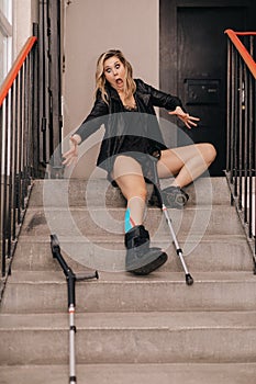 Young woman falling on stairs. Broken leg in an orthosis and crutches. Disabled person . Life insurance