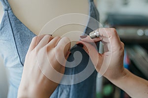 Young woman fashion designer measuring mannequin, seamstress holding tape working with dummy in cozy home or tailor shop,