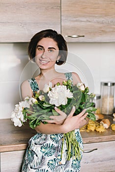 Young woman in fashon dress holding bouquet of beautiful white peonies flowers