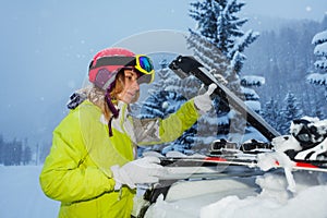 Young woman fastening skis on the roof of car