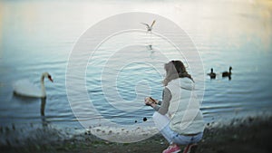 A young woman feeding on a lake swans and ducks Bird feeding in winter