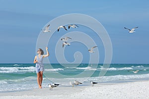 Young woman feeding seagulls on tropical beach, Florida photo