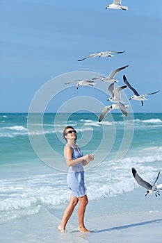 Young woman feeding seagulls on tropical beach, Florida photo
