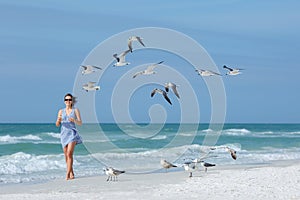 Young woman feeding seagulls on tropical beach, Florida photo