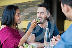 Young woman feeds salad to man
