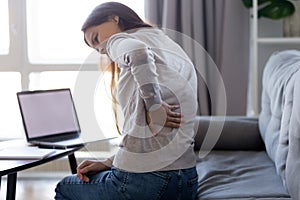 Young woman feeling backpain after sedentary computer work at home