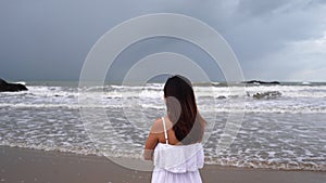 Young woman feeling lonely and sad looking at the sea on a gloomy day