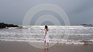 Young woman feeling lonely and sad looking at the sea on a gloomy day