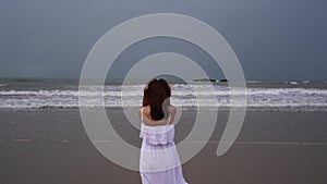 Young woman feeling lonely and sad looking at the sea on a gloomy day