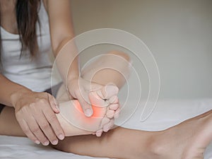 Young woman feeling pain in her foot at home.