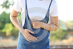 Young woman feeling pain with her stomachache on nature green background, Healthcare and Medicine concep