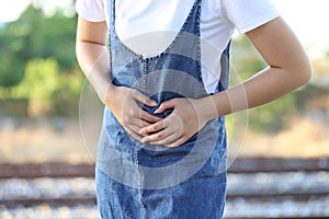 Young woman feeling pain with her stomachache on nature green background, Healthcare and Medicine concep