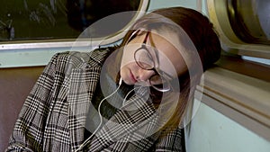 A young woman fell asleep on a subway train. Girl with headphones in the ears. Old subway car