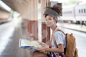 Young woman female smiling traveler with back pack looking to map while waiting for the train at train station