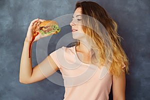 Young woman fighting temptation to eat burger