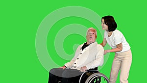 Young woman finally taking her disabled father in a wheelchair home on a Green Screen, Chroma Key.