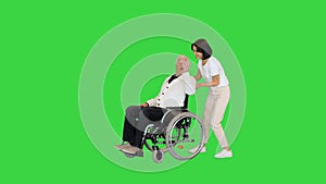 Young woman finally taking her disabled father in a wheelchair home on a Green Screen, Chroma Key.