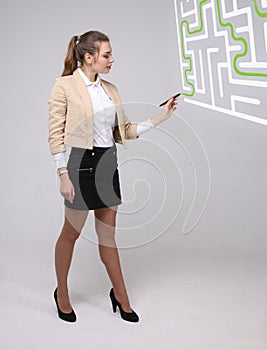 Young woman finding the maze solution, writing on whiteboard.