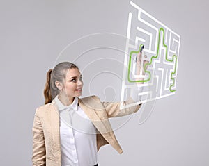 Young woman finding the maze solution, writing on whiteboard.