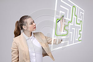 Young woman finding the maze solution, writing on whiteboard.