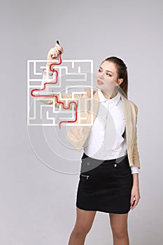 Young woman finding the maze solution, writing on whiteboard.