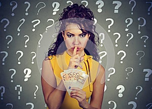 Young woman with finger on lips gesture and euro banknotes in hand