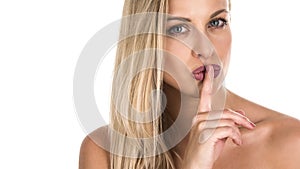 Young woman with a finger near her lips. Studio shot. Isolated on white background