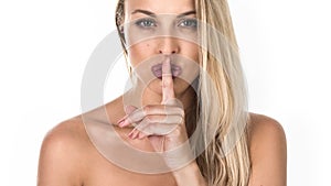 Young woman with a finger near her lips. Studio shot. Isolated on white background