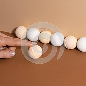 Young woman fingers touch the organic bath bombs with shadow on beige background. Spa concept. Presents for body