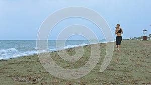 Young woman with fit body jogging on sandy beach in the morning. Health care