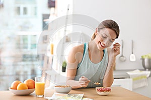 Young woman in fitness clothes having breakfast at home