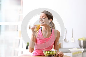 Young woman in fitness clothes having breakfast at home