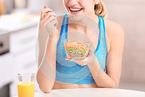 Young woman in fitness clothes having breakfast at home, closeup