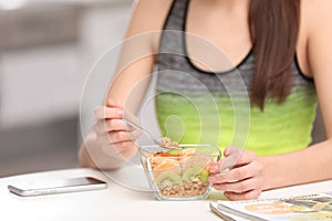 Young woman in fitness clothes having breakfast at home, closeup