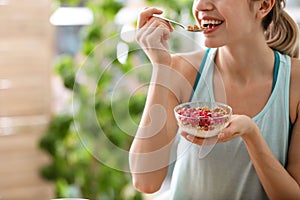 Young woman in fitness clothes having breakfast at home, closeup. Space for text