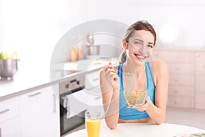 Young woman in fitness clothes having breakfast at home. Space for text